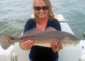 Lady holding up a pretty spotted red drum.